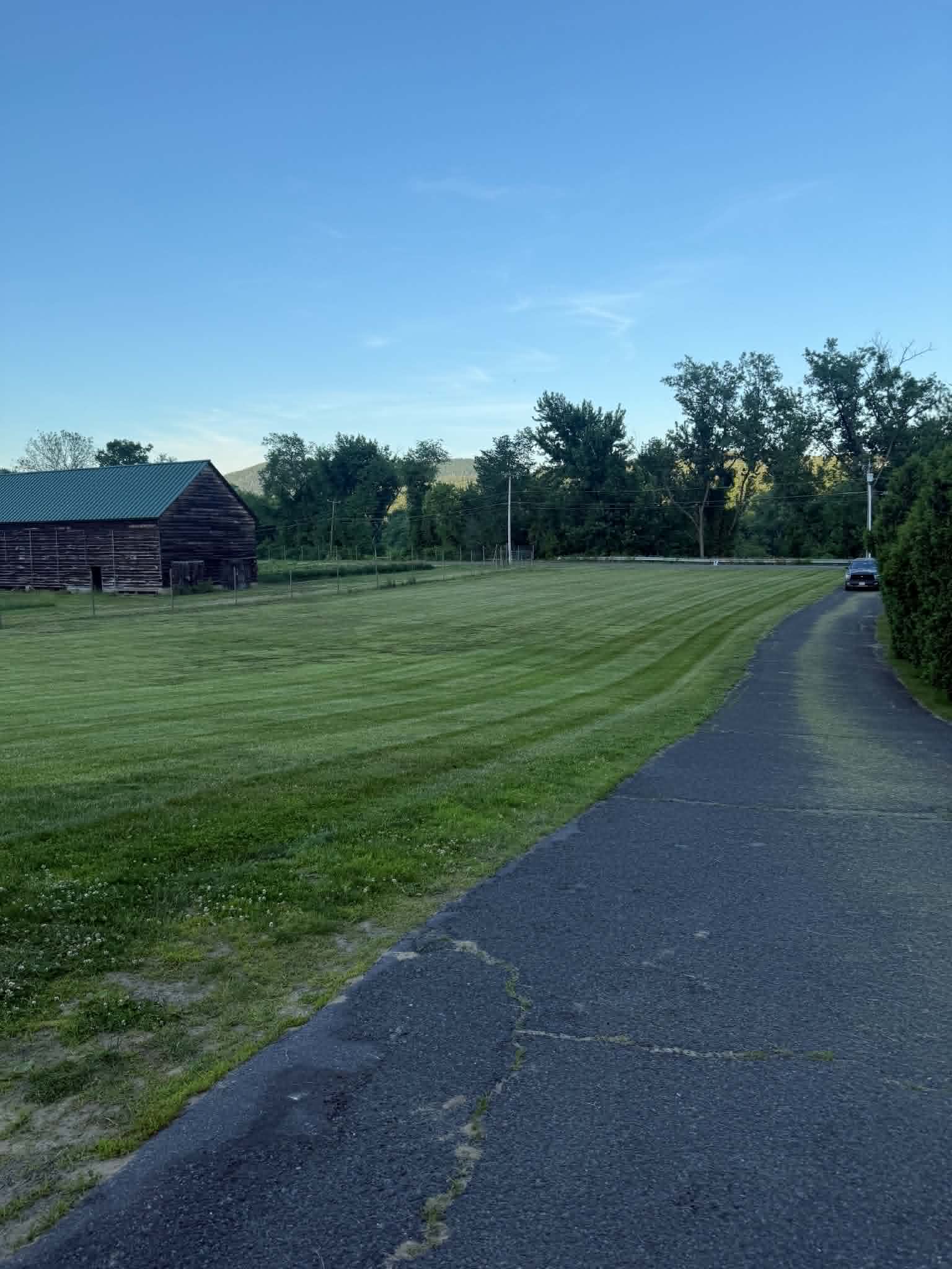 Freshly mowed lawn beside a driveway and barn